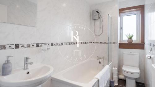 a white bathroom with a sink and a toilet at The Den at Braehead in Cruden Bay