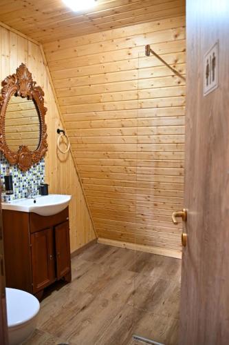 a wooden bathroom with a sink and a mirror at Carpatina A-Frame Retreat - Rustic Cabins for Couples in Runcu