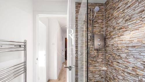 a shower in a bathroom with a brick wall at The Den at Catto in Peterhead