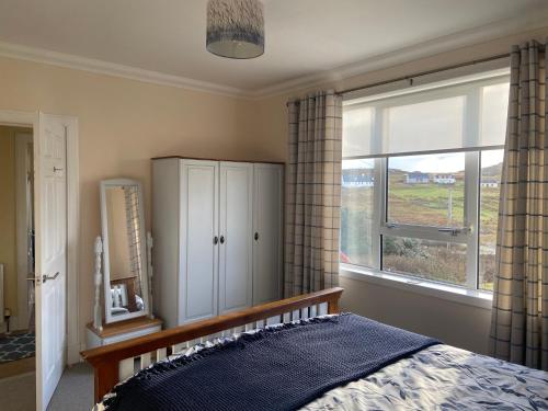 a bedroom with a bed and a large window at Tigh-na-Greine in Carloway