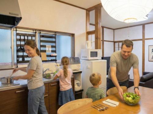 a man and a woman and two children in a kitchen at Private House HidaTakayama - Cozy Family Home in Takayama