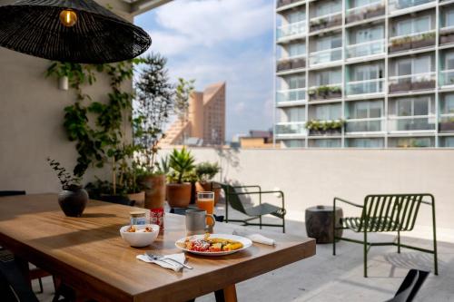 a wooden table with a bowl of food on a balcony at Capitalia Antara Polanco in Mexico City