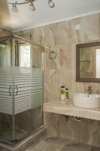 a bathroom with a glass shower and a sink at Pargamaisonnette in Parga