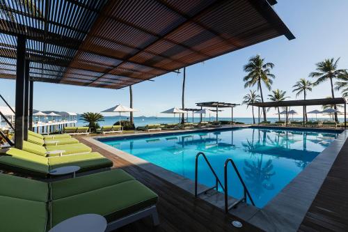 a pool with chairs and the ocean in the background at Coral Sea Resort in Airlie Beach
