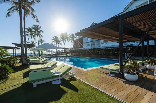 a row of lounge chairs next to a swimming pool at Coral Sea Resort in Airlie Beach