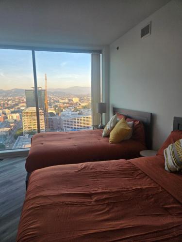 two beds in a room with a large window at 2 Bedroom with City Views in Los Angeles