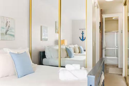 a bedroom with a mirror and a white bed at Beachfront Resort-sunset views deck & luxe king in Oceanside