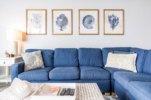 a blue couch in a living room with four pictures on the wall at Caribe 305C by Youngs Suncoast in Orange Beach