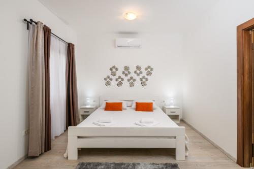 a white room with a bed and two orange pillows at Villa Percan - Spacious Family Home with Private Pool on a 4000 Square Meter Plot in Krnica