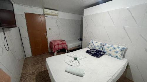 a small room with a white bed with pillows at Pousada Rosario in Malhada dos Bois
