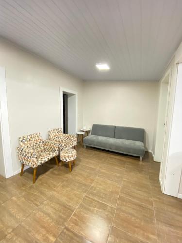 a room with a couch and two chairs and a table at Casa central in Rosário do Sul