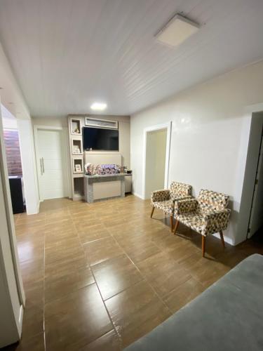 a living room with two chairs and a television at Casa central in Rosário do Sul