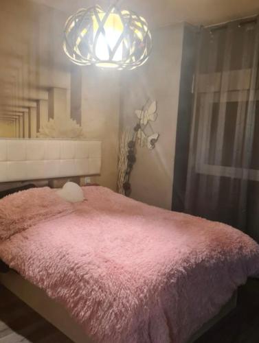 a bedroom with a pink bed and a chandelier at Apartamento Deluxe city in Burgos