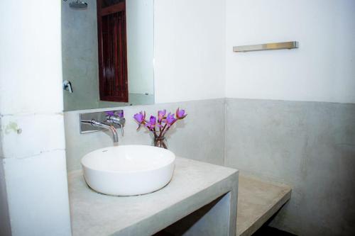 a bathroom with a sink and a vase of purple flowers at Casa Hikka Villa in Sinigama