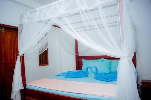 a bedroom with a canopy bed with blue pillows at Casa Hikka Villa in Sinigama