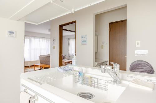 a white bathroom with a sink and a mirror at つぐ屋札幌 in Sapporo