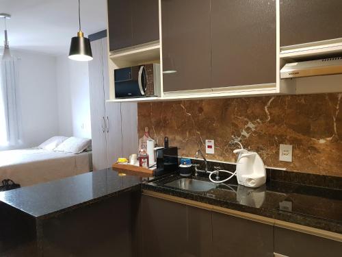 a kitchen with a sink and a bed in a room at Flat Novo1 - Café, Cama Queen, Ar, Estac e Internet in Barueri