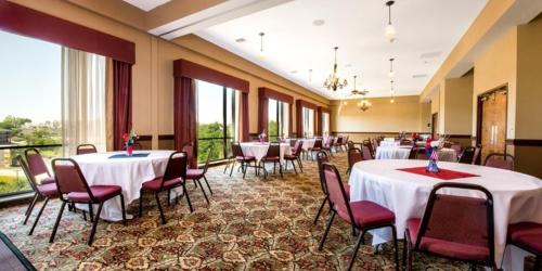 a banquet hall with white tables and chairs and windows at Grand Plaza Hotel & Conference Center in Branson