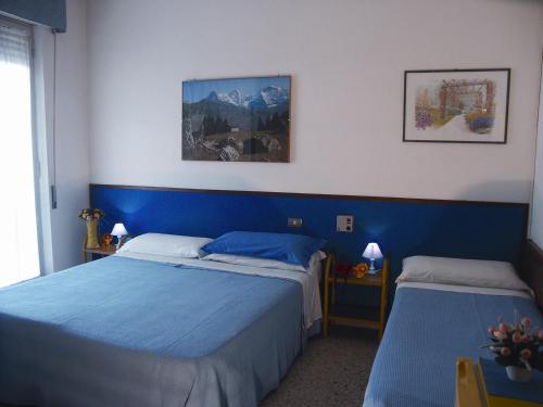 two beds in a room with blue walls at Hotel Bologna in San Benedetto del Tronto