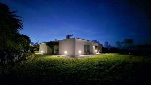 a white house with lights on a grassy yard at night at Seaview Villa with Heated Private Pool in Bretanha