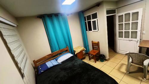 een slaapkamer met een bed en een blauw gordijn bij Alba Hostel in Sucre