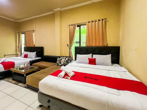 a hotel room with two beds and a couch at RedDoorz at Dieng 0KM in Diyeng