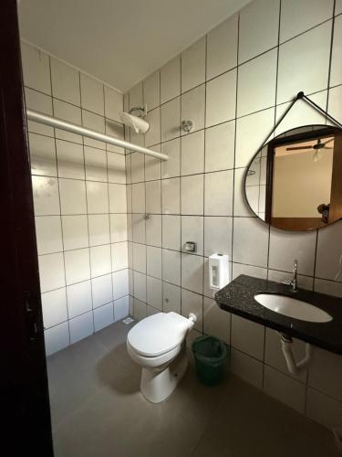 a bathroom with a toilet and a sink and a mirror at Hotel Valle in Patrocínio