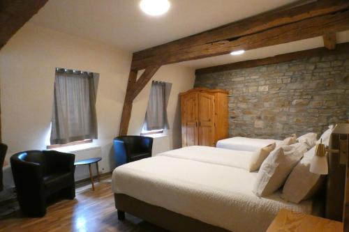 a bedroom with a large bed and a stone wall at Schmiede Hotel in Schoenberg
