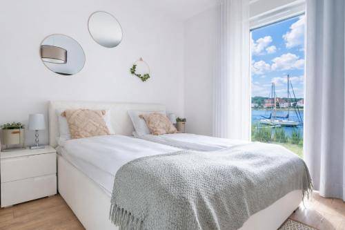 a white bedroom with a bed and a window at Port View - widok, 15m do jeziora, ogródek, parking podziemny, winda, Netflix i Prime in Iława