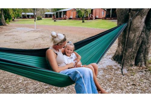 a woman and a child sitting in a hammock at Discovery Parks Margaret River in Cowaramup