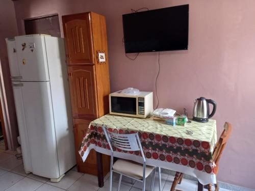 a kitchen with a table with a microwave and a refrigerator at kit net Rua Ildo Meneghetti, 160 in Alegrete