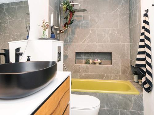 a bathroom with a black sink and a yellow tub at Nature Escape Forest & Lake Access in Viborg
