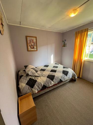 a bedroom with a bed with a checkered blanket at Espaciosa casa familiar en Queule in Nehuin