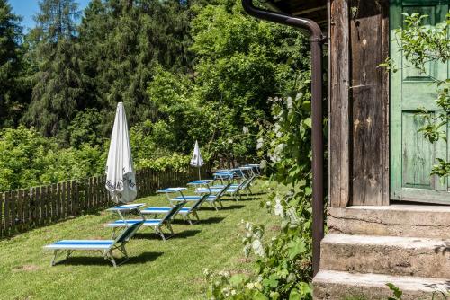a row of chaise lounges and an umbrella at Naturhotel Waldheim in Anterivo