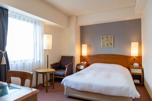 a bedroom with a bed and a table and a chair at Mori-no-Hotel Sendai in Sendai
