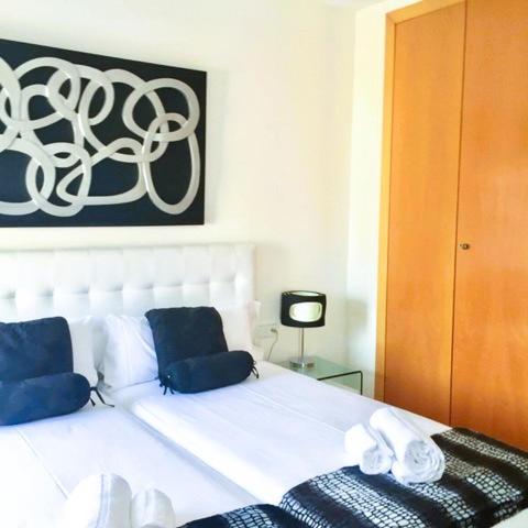 a white bed with blue pillows in a bedroom at Attic Center Sitges in Sitges