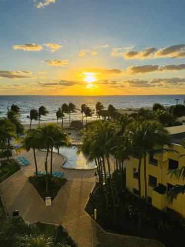 a sunset over the ocean and a resort with palm trees at Oceanfront retreat, Hollywood Beach ,Miami Florida in Hollywood
