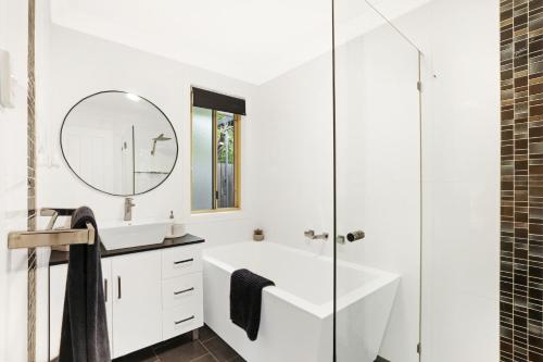a white bathroom with a sink and a mirror at Belle in Bowral in Bowral