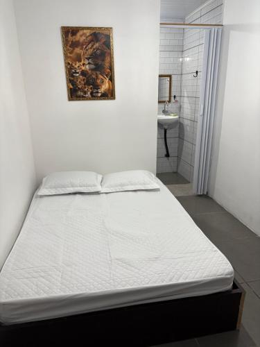 a white bed in a room with a bathroom at Pesqueiro & Pousada Beatriz in Piedade