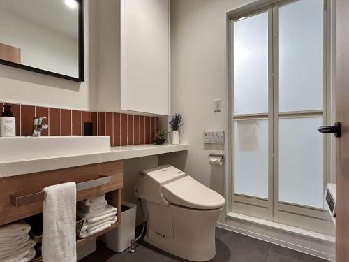 a bathroom with a toilet and a sink at Akayane Lodge by H2 Life in Nakafurano