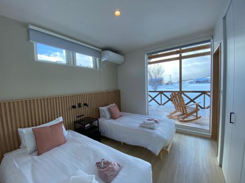 a bedroom with two beds and a balcony at Akayane Lodge by H2 Life in Nakafurano