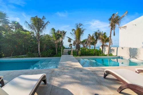 an infinity pool with palm trees and a villa at Akumal Cielo Seven Ocean View Pools Beach Access in Akumal