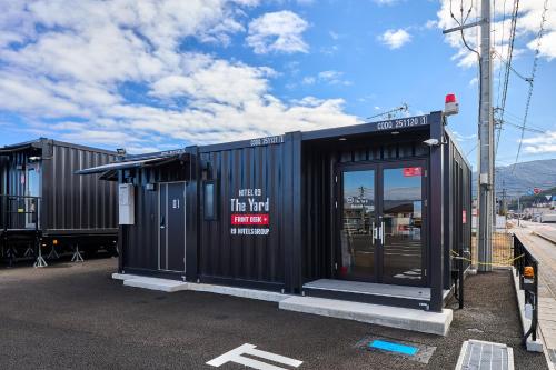 a black building with a door in a parking lot at HOTEL R9 The Yard Enabekkan in Ena