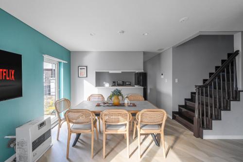 a dining room with a table and chairs and a staircase at The KAMUY FURANO in Nakafurano