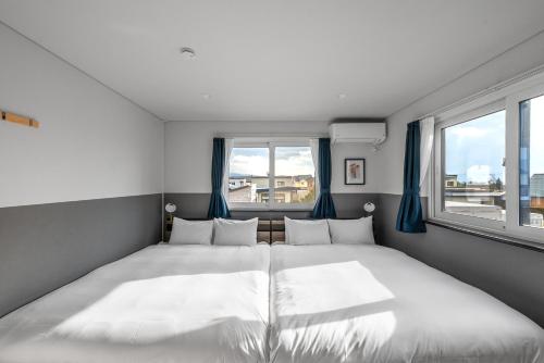 a bedroom with two beds and two windows at The KAMUY FURANO in Nakafurano
