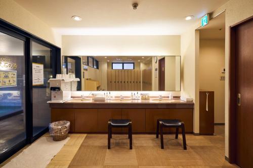 a bathroom with two stools and a large mirror at Hotel Lexton Kagoshima in Kagoshima