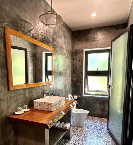 a bathroom with a sink and a toilet and a mirror at Ocean House An Bang in Hoi An