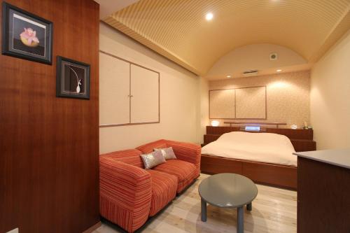 a living room with a couch and a bed at HOTEL DCUBE in Tokyo