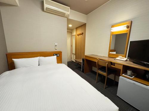 a hotel room with a bed and a desk and a mirror at Hotel Route-Inn Nakatsugawa Inter in Nakatsugawa