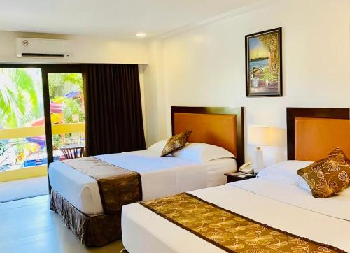a hotel room with two beds and a window at Paradise Station 3 Garden Boracay Resort by JustGoFun in Boracay